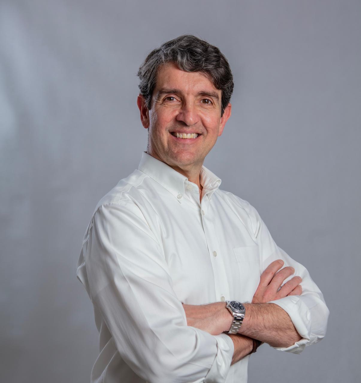 Retrato profissional de Lancha Junior, de camisa branca e braços cruzados